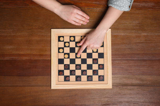 istock Playing checkers. Woman thinking about next move at wooden table, top view 1779371591