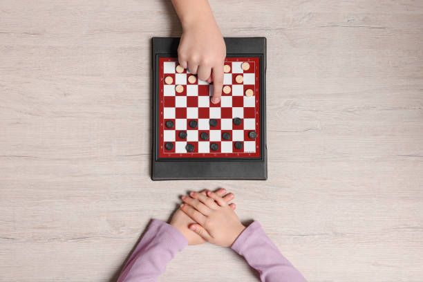 istock Children playing checkers at light wooden table, top view 1779371596