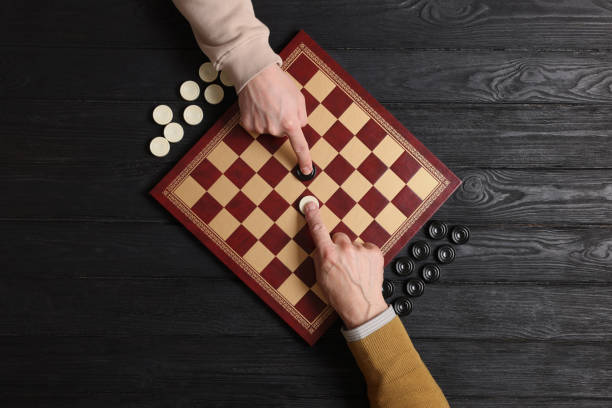 homem jogando damas com parceiro na mesa de madeira preta, vista superior - board game success victory winning - fotografias e filmes do acervo