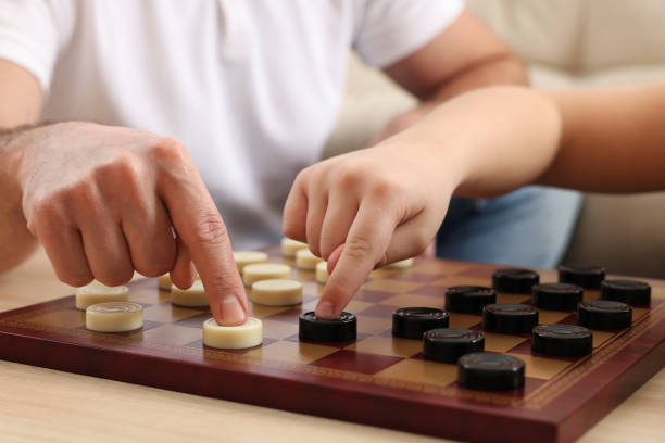 istock Father playing checkers with his son at table in room, closeup 1779372163