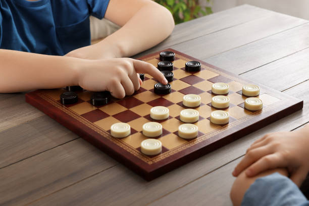 istock Children playing checkers at table in room, closeup 1779372186