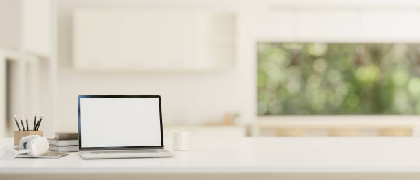 istock A white-screen laptop mockup on a white tabletop with a blurred background of a modern white room. 1779475612