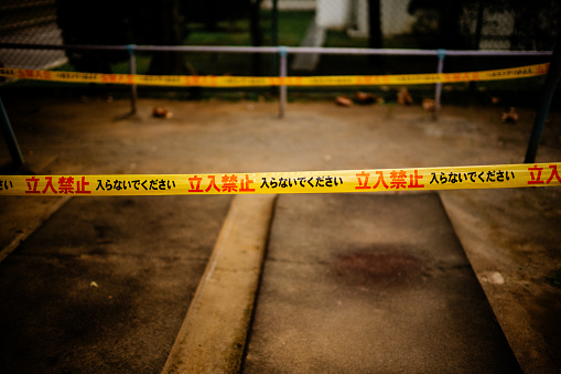Police line do not cross on dark concrete wall background. Crime scene banner with copy space for true crime stories or investigations podcast.