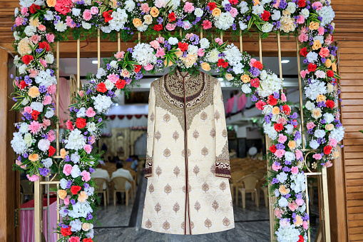 A closeup of groom wedding sherwani or male wedding costume hanging in wedding hall with decoration