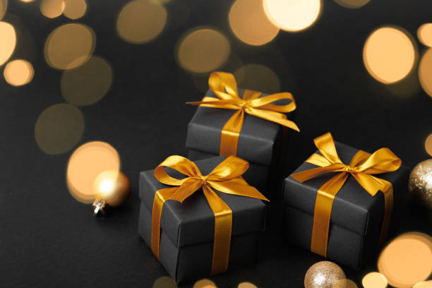 istock Black gift box with golden ribbon bow on black background 1779595658
