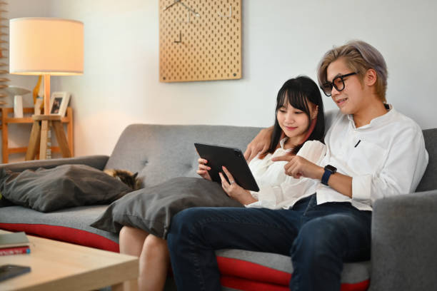 istock Relaxed young Asian couple watching video on digital tablet and spending weekend time together at home 1779597918