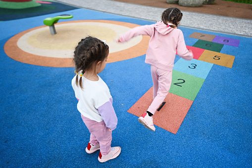 Back view of two girls playing hopscotch game at playground