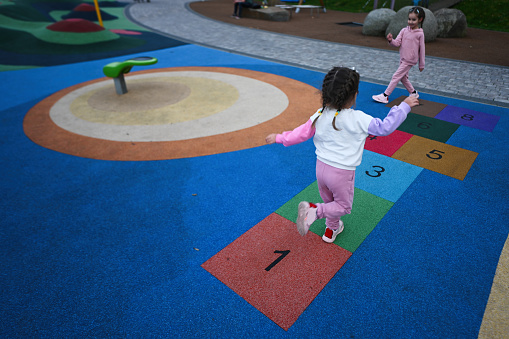 Little girl playing hopscotch at playground in the park.