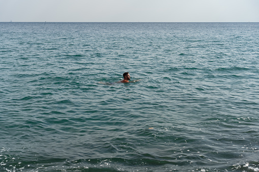 A man with a beard swims in the blue sea near Athens. High quality photo