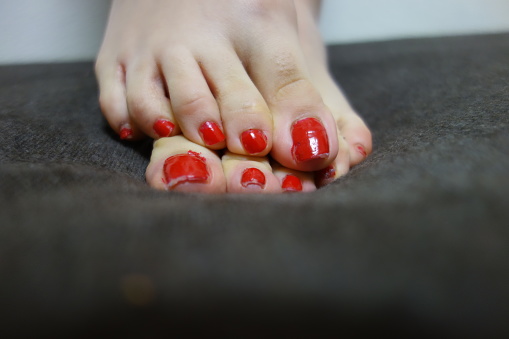 Female feet with red nail polish against clear blue sky