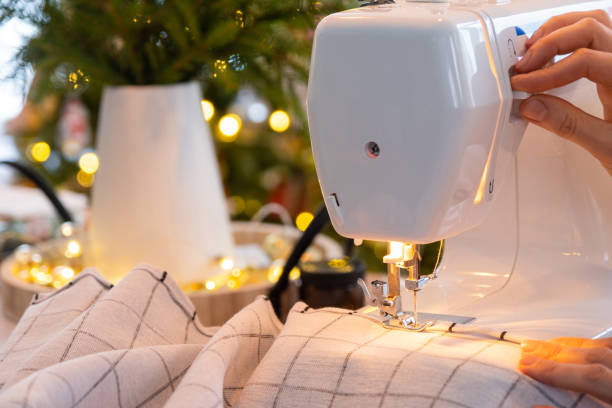 istock Sewing process on a sewing machine, women hands control needle with a thread white checkered fabric. Preparation for Christmas and new year, textiles for cozy in festive decor interior 1779637386