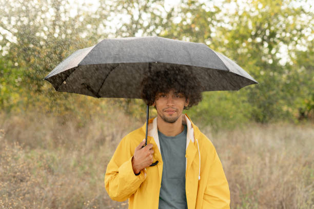 istock Arabic guy holding umbrella while strolling outside. He is looking at camera with true delight and sincere smile. 1779656831