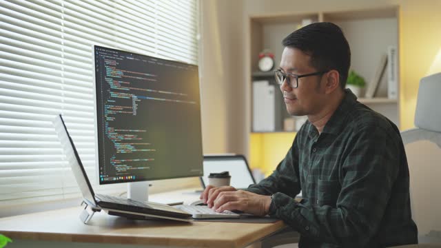 Software develper asian man wearing glasses working coding Write a program develope AI application on laptop at home office.