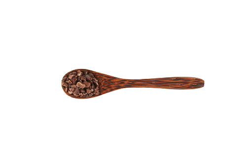 Cocoa nibs in wooden spoon on white background. Crunchy pieces of peeled, crushed and lightly roasted cocoa beans with pleasant chocolate bitterness. Sugar-free product. Design element.