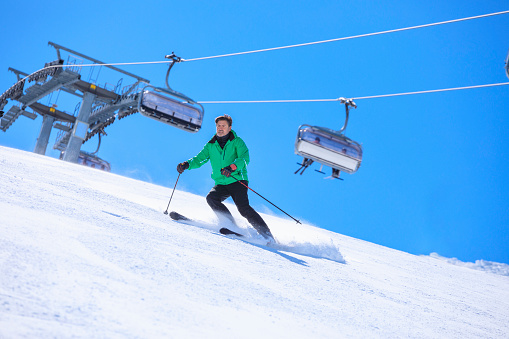 Active lifestyle, Vital senior men snow skier skiing, enjoying on sunny ski resorts. Skiing carving at high speed.  Alps  ski area. Ski resort Livigno. italy, Europe.