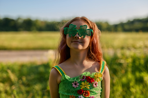 Adorable 9 year old girl with red hair celebrates Saint Patrick's Day on the 17th of March dressed as a green pixie or leprechaun