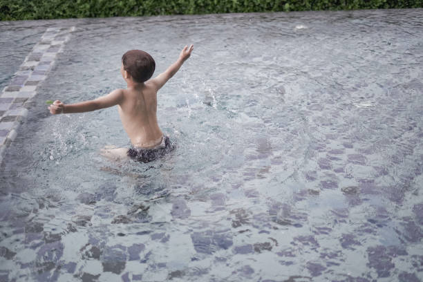Boy playing in the swimming pool when it rains