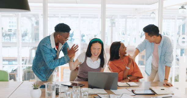 istock High five, laptop and a designer team in celebration at the office together for work on a creative assignment. Computer, meeting or teamwork with an employee group cheering for success or support 1779728463