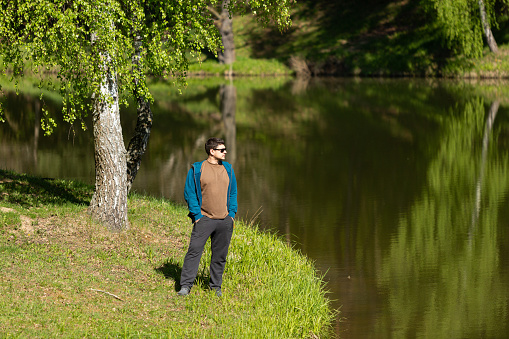 A man in sunglasses stands on the shore of the lake