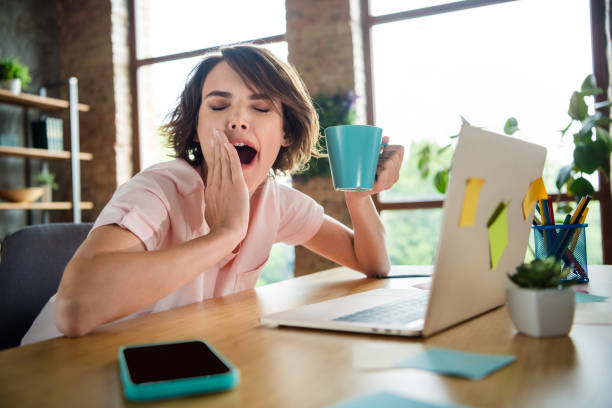 foto di giovane divertente signora esausta tenere la tazza di caffè mattutino che sbadiglia dopo una lunga lezione universitaria isolata sullo sfondo dell'appartamento - yawning women drink coffee cup foto e immagini stock