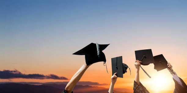 istock Four hands holding graduation hats against sunrise sky 1779741258