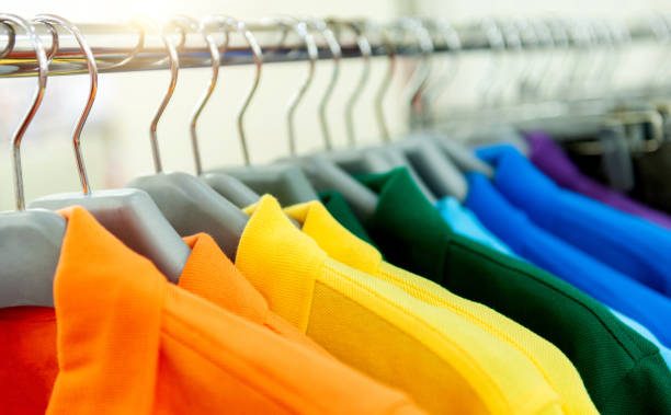 bunte poloshirts auf kleiderbügeln in einer reihe - polo shirt multi colored clothing variation stock-fotos und bilder