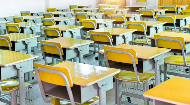 Empty classroom with desks and chairs in a line stock photo