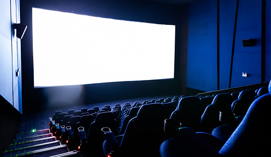 Dark movie theatre interior with screen and chairs