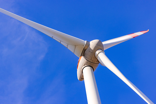 Details of rotor and blades of a wind turbine cropped in front of a blue sky
