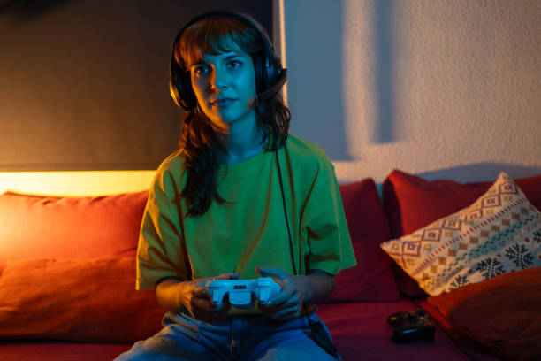istock Woman alone playing console using headphones at home at night 1779764375