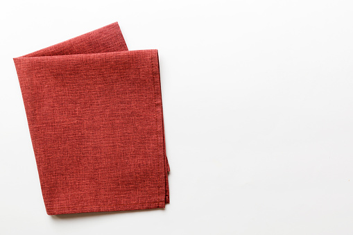 top view with red empty kitchen napkin isolated on table background. Folded cloth for mockup with copy space, Flat lay. Minimal style.