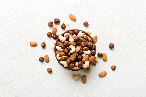Close up view of a glass bowl filled with peanuts shot on dark rustic table.