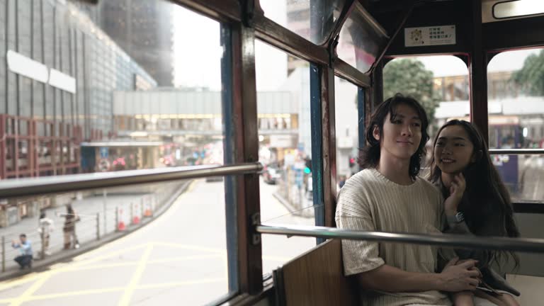 Asian Chinese couple enjoy travelling in double decker bus exploring Hong Kong attraction places