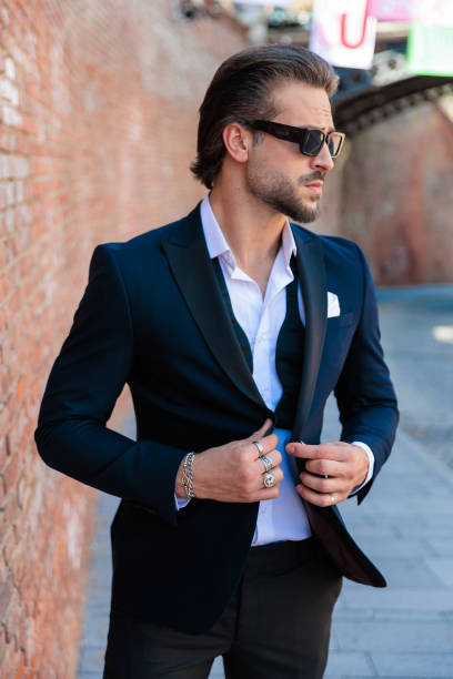 istock handsome elegant man with glasses looking to side and buttoning suit 1779771881
