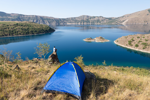 A young traveler is camping on the shore of a lake.