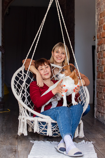 Senior mother and middle age daughter take a time together in swing at home