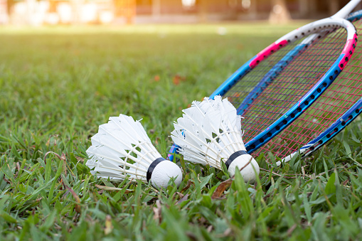 Badminton sport equipments, rackets and shuttlecocks on grass lawn, blurred background, concept for outdoor sport exercise.