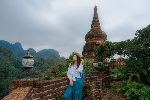 Elegant female traveler looking at jungles from the temple in Thailand