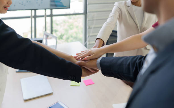 istock Corporate professionals engaging in firm join hands marking collaboration, inside a modern office setting. 1779812610