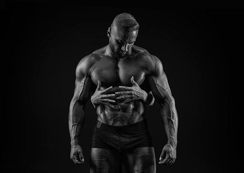 Perfect abdomen. Female hands embracing, touching muscular man abs isolated over black background. Sports, workout, bodybuilding concept. Front view. Horizontal shot