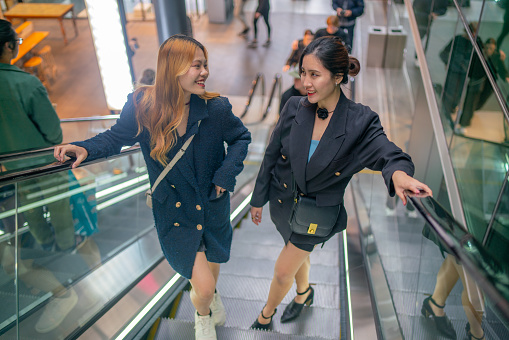 Two friends chatting as they take the escalator