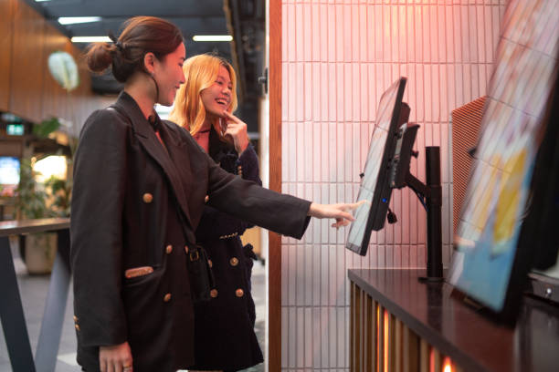 Ordering On Touch Screen Kiosk Two friends ordering a meal on touch screen kiosk kiosk stock pictures, royalty-free photos & images