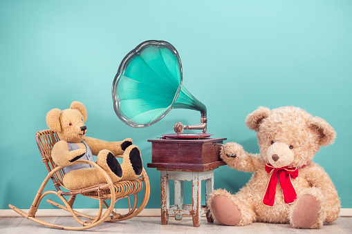 Teddy Bear toys sitting near vintage gramophone phonograph front mint blue background. Nostalgic music concept. Retro style filtered photography