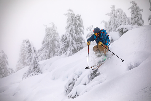 Young back country skier riding off-piste in deep snow