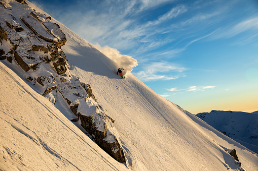Freeride skier riding untouched back country terrain just before sunset