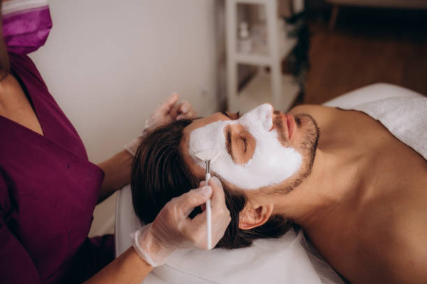 istock Cosmetologist applying mask on client's face in spa salon, above view 1779871524