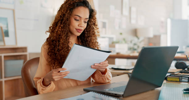 istock Woman, laptop and documents for creative strategy, research or reading in schedule planning at office. Female person with paperwork for project plan, finance or startup ideas on computer at workplace 1779891311