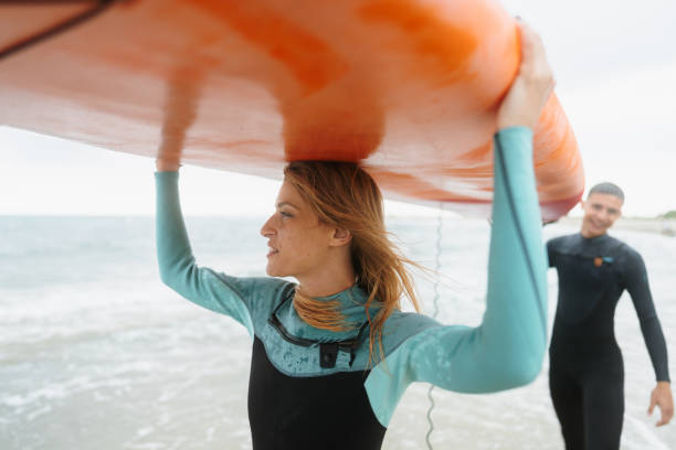istock Couple of surfers carrying a surfboard 1779900867