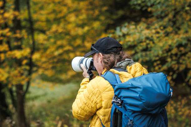 istock Man with backpack is wearing yellow jacket and photographing at his camera 1779920978