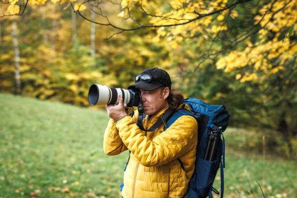 istock Hiker with backpack is wearing yellow jacket and photographing at his camera 1779920986